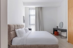 Een moderne hotelkamer met een groot bed, een bureau en een garderobe.