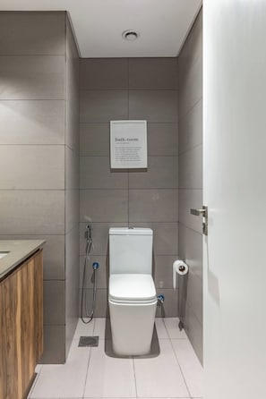 Een moderne badkamer met toilet, douche en een bordje erboven.
