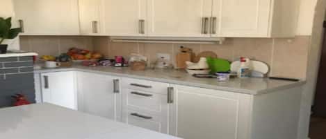 A kitchen with white cabinets, a countertop, and various kitchen items.
