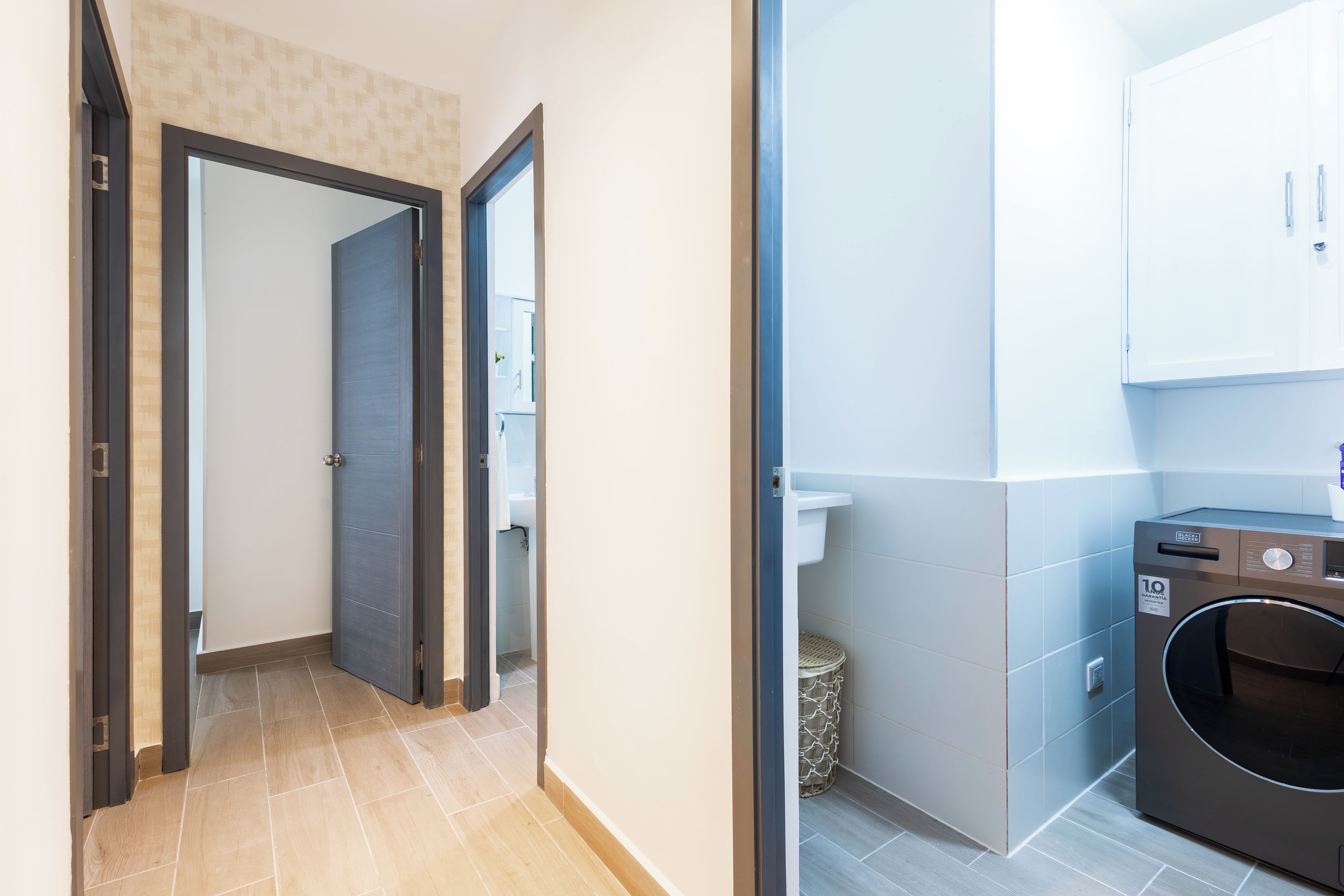 A hallway leading to a bathroom with a toilet and a washing machine.