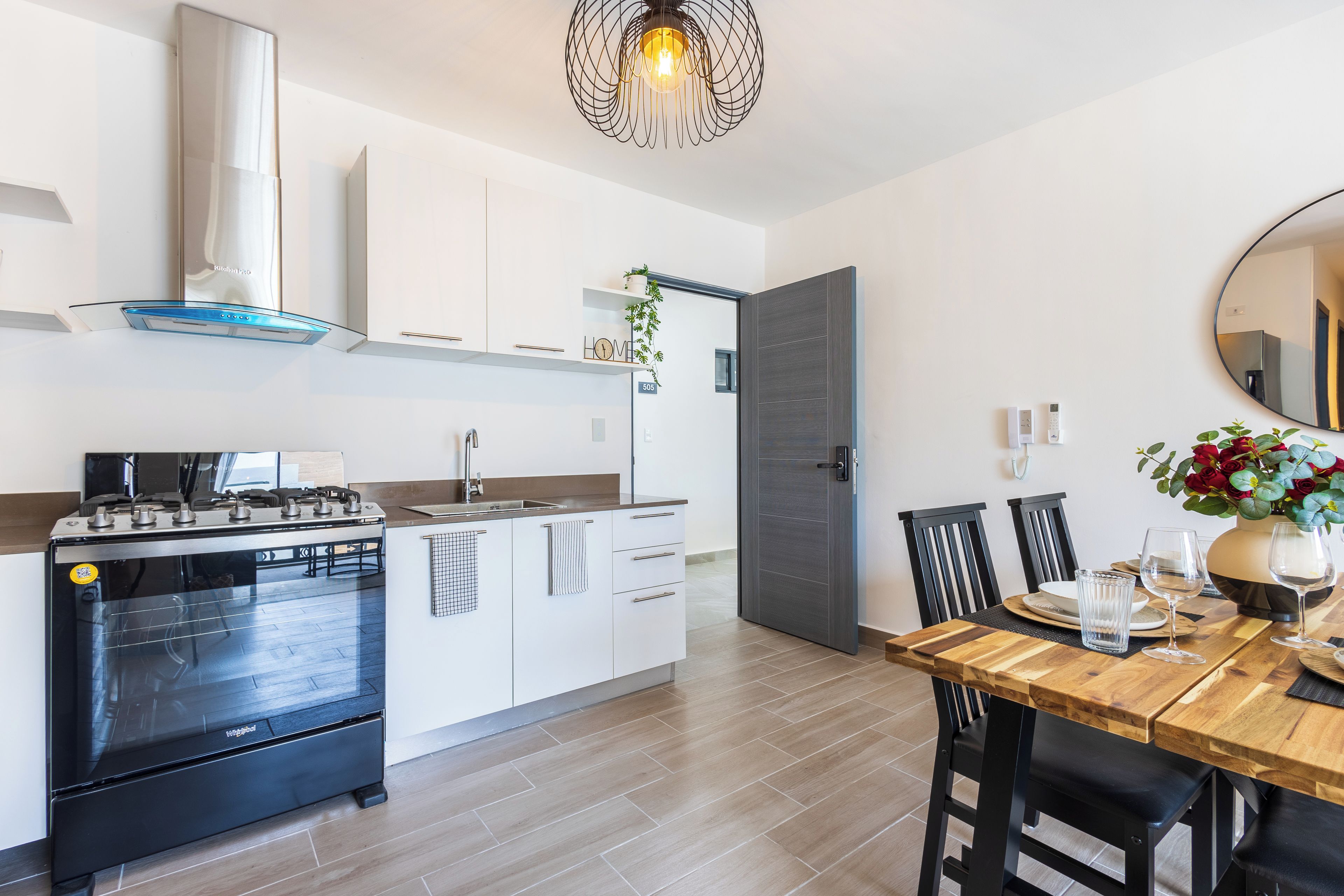 Une cuisine moderne équipée d’une cuisinière, d’un four et d’un coin repas avec des chaises et une table.