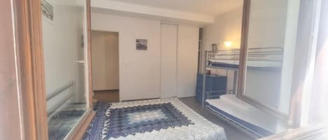 Una habitación con una litera, un escritorio pequeño y una alfombra estampada.