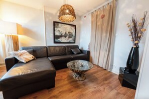 Ein modernes Wohnzimmer mit einem Ecksofa, einem Glastisch und einer dekorativen Vase.