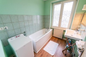 Ein Badezimmer mit einer Badewanne, einem Waschbecken und einem Fenster.