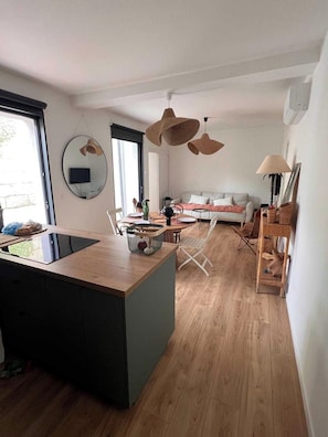 Eine moderne Küche mit einer zentralen Kochinsel, einem Essbereich mit einer Couch und einem Wohnbereich mit Fernseher.
