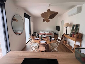 Ein modernes Wohnzimmer mit einem runden Esstisch, einer Couch und einem großen Spiegel.