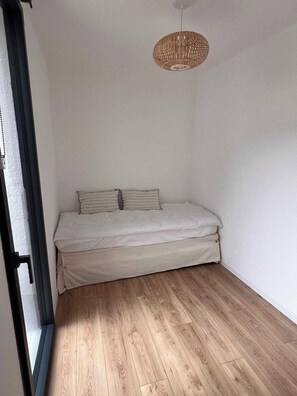 Ein Zimmer mit einem Bett, Holzboden und einer Pendelleuchte.