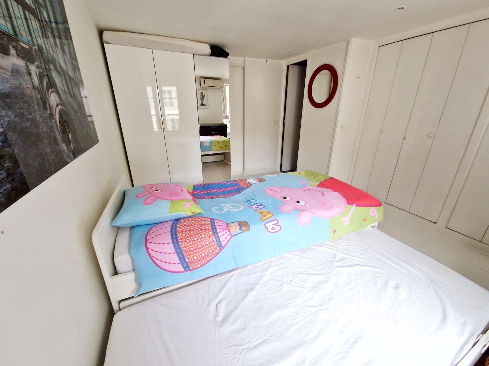 Quarto com cama, guarda-roupa e espelho.