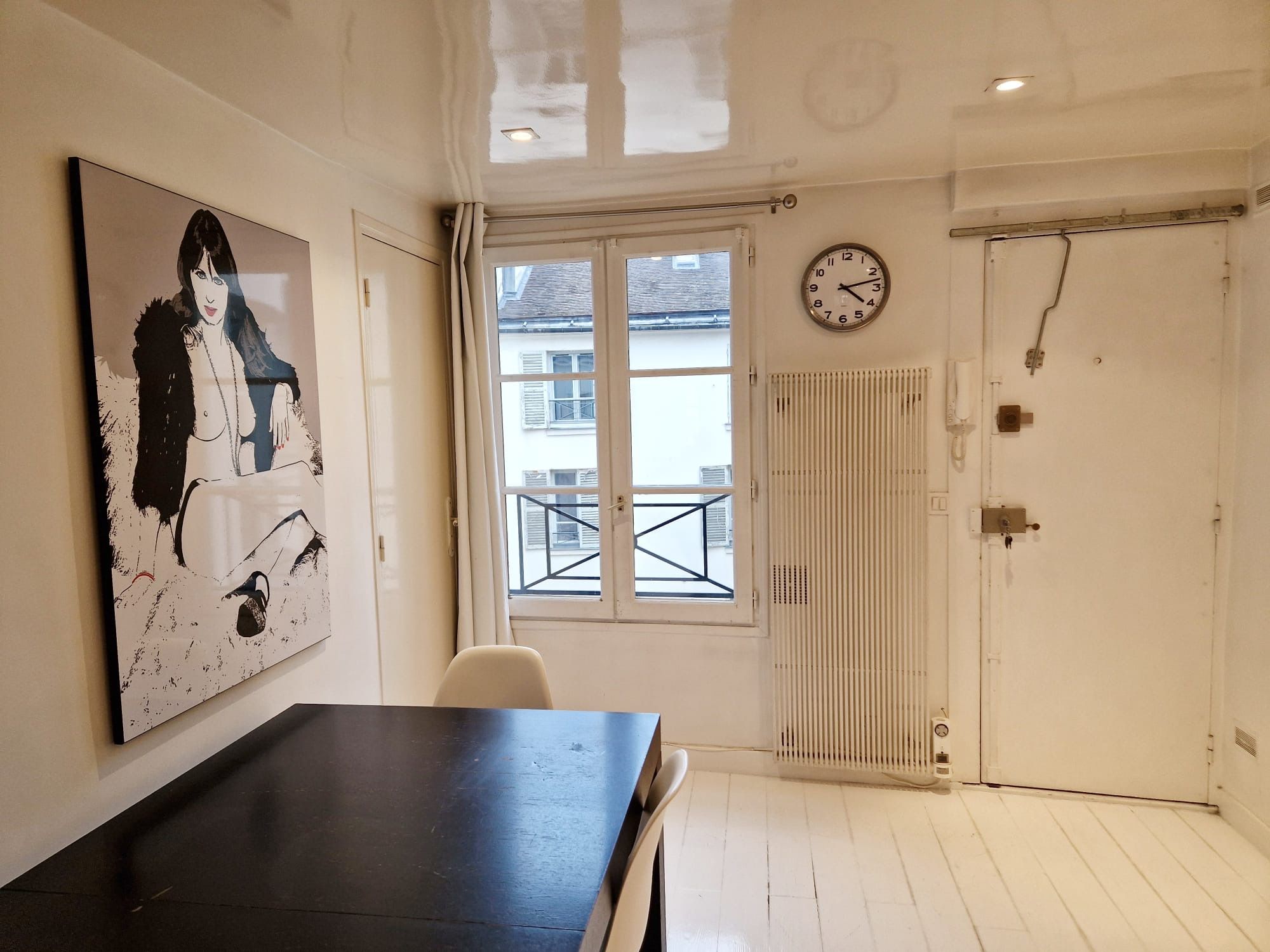 Quarto com uma pintura grande na parede, um relógio, um radiador e uma porta.