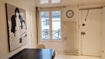 Una habitación con un cuadro grande en la pared, un reloj, un radiador y una puerta.