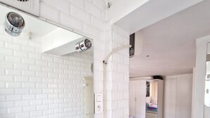 Ein modernes Badezimmer mit weiß gefliesten Wänden, einem großen Spiegel, einer weißen Badewanne und einer Dusche.