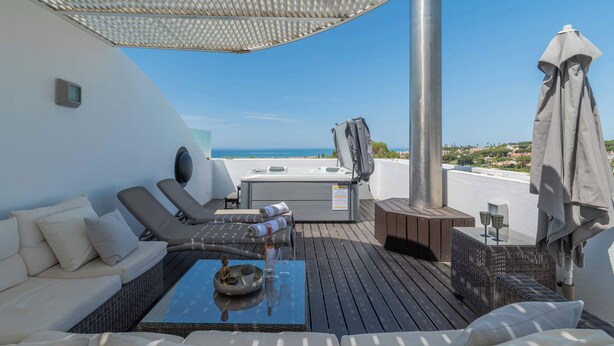 Eine Dachterrasse mit Whirlpool, Liegestühlen und Meerblick.