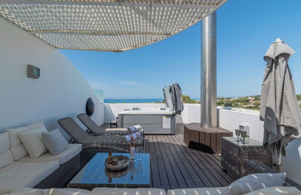 A rooftop terrace with a hot tub, lounge chairs, and a view of the sea. - Vrbo Property (Faro)