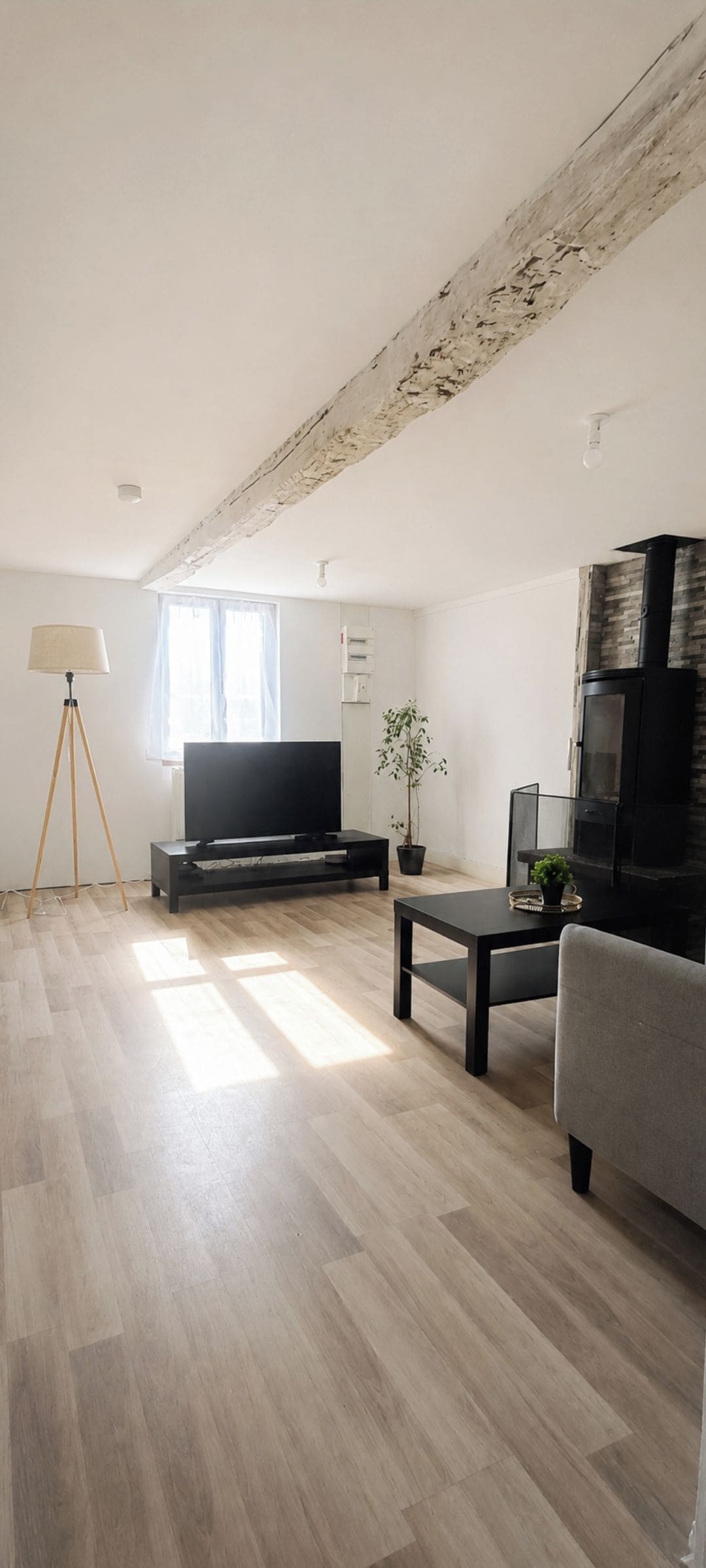 A modern living room with a flat-screen TV, a coffee table, a sofa, a floor lamp, and a fireplace.