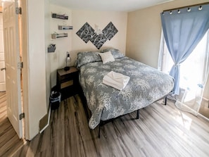 Een slaapkamer met een bed, nachtkastjes, een wandlamp en een raam met gordijnen.