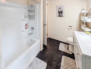 Een badkamer met bad, toilet en wastafel.