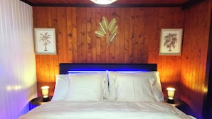 Ein Bett mit weißen Leinentüchern, Holzwänden und zwei Wandleuchten.