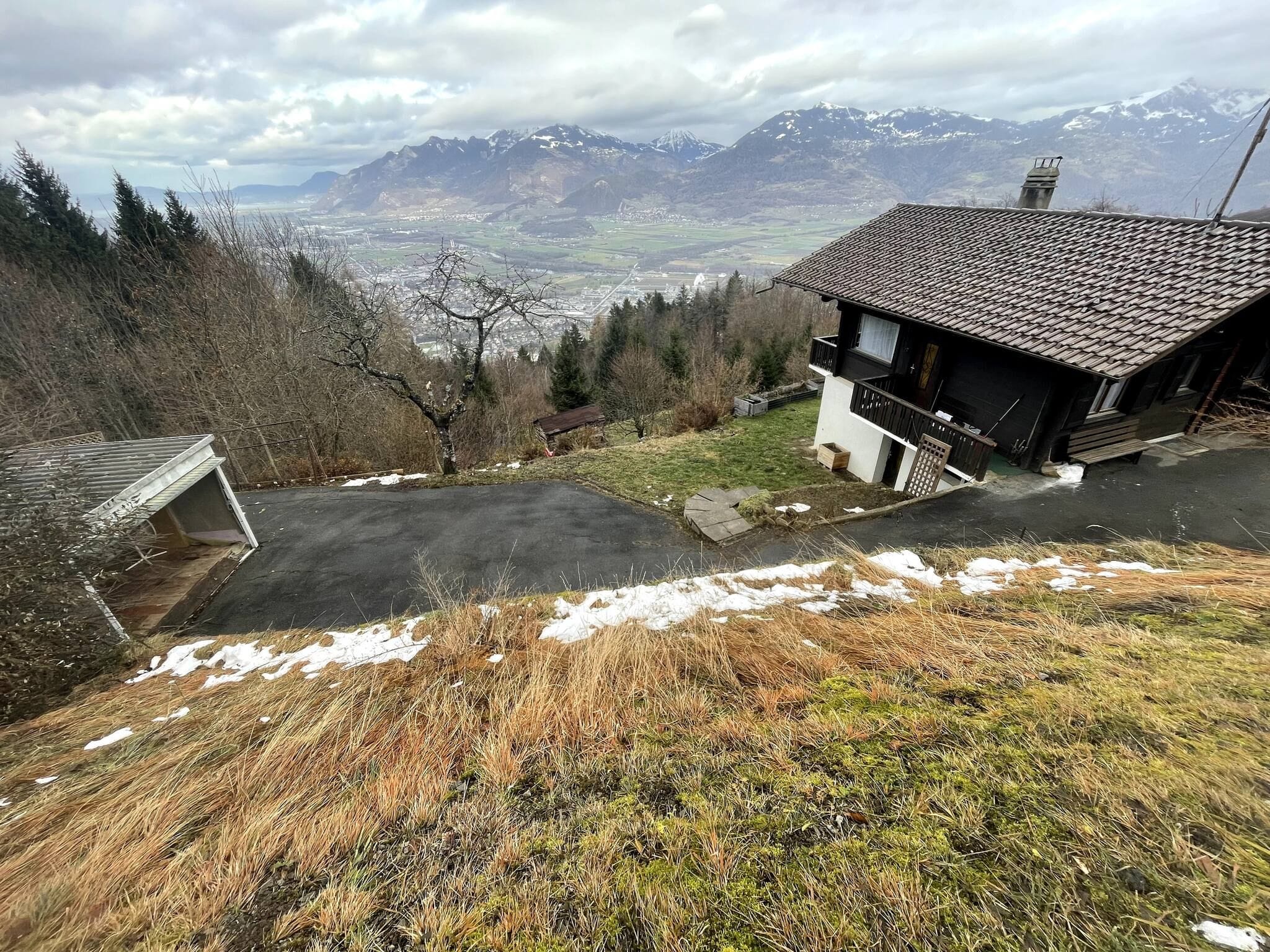 A house with a sloped roof, a garage, and a view of mountains in the background.