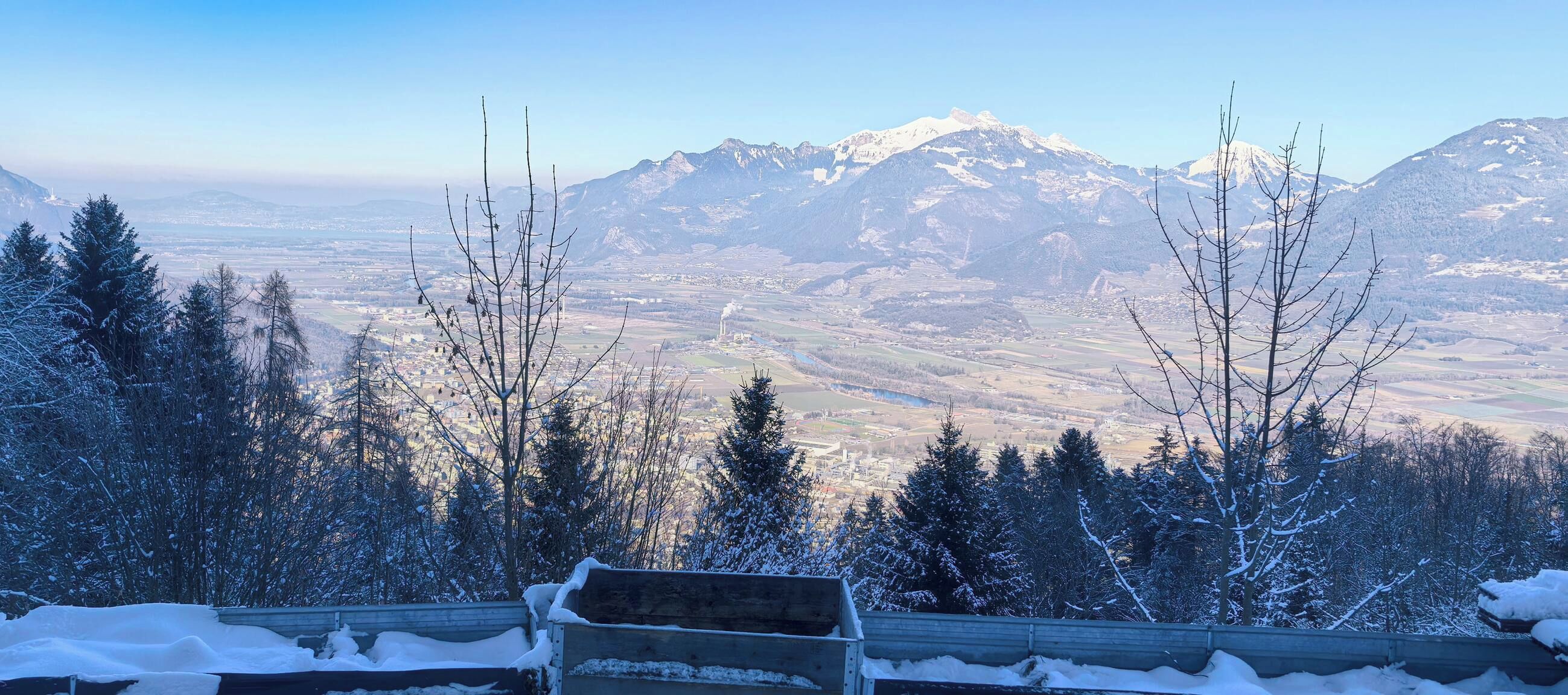 Um banco com vista para uma paisagem coberta de neve e montanhas ao longe.