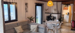 A cozy living room with a grey sofa, a white dining table with chairs, and a hanging light fixture. - Chalet L'appel Giettes (Monthey)