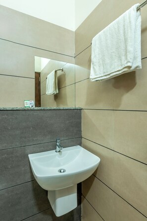 Uma casa de banho com lavatório, espelho e porta-toalhas.