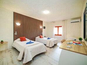 A hotel room with two beds, a wooden panel wall, a desk with a remote control, and an air conditioning unit. - Dencis Villa by Interhome (Calpe/Calp)