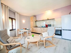 A modern kitchen with a microwave, toaster, and stove. There is a dining area with a table and chairs. - Dencis Villa by Interhome (Calpe/Calp)