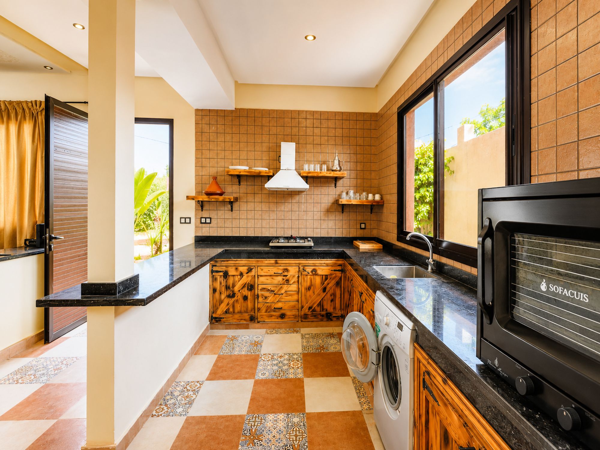 A compact kitchen with a washing machine, a stove, and a large window.