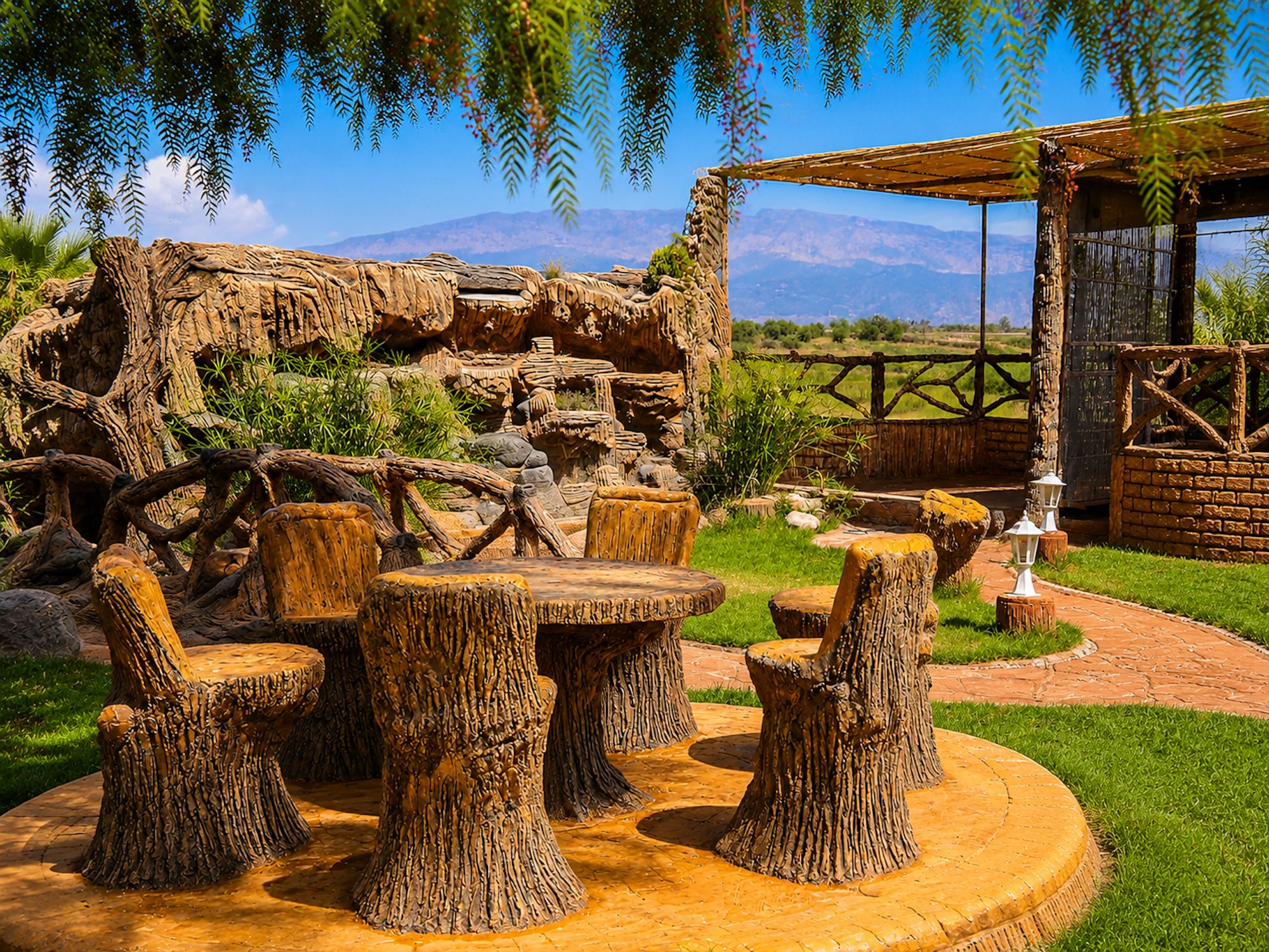 A rustic outdoor seating area with wooden tables and chairs, surrounded by a natural landscape with a view of distant mountains.