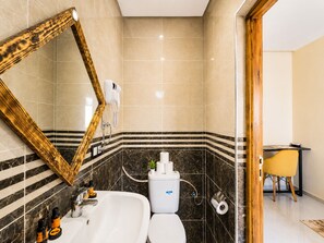 Un baño con un espejo grande, una bañera, un inodoro y una zona de ducha.