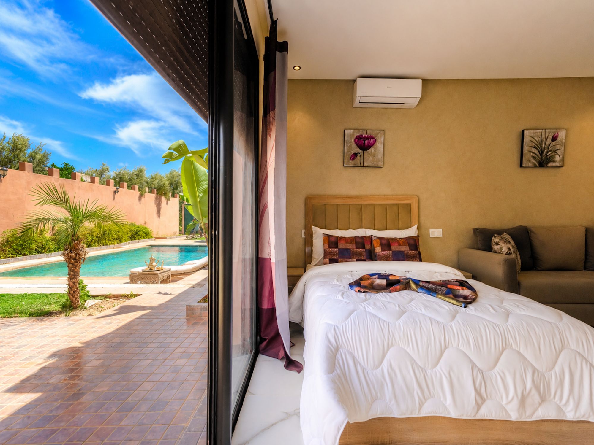Habitación de hotel con cama, vista a una piscina y un equipo de aire acondicionado en la pared.