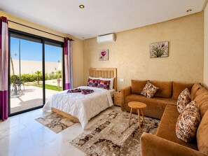 A bedroom with a bed, a sofa, a small table, and a window with curtains. - Villa Inaya - Marrakesh (Marrakech)