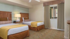 Habitación de hotel con dos camas, una ventana con cortinas, un ventilador de techo y piso alfombrado.