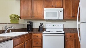 Una cocina con armarios de madera, un microondas blanco, una estufa y un lavavajillas.