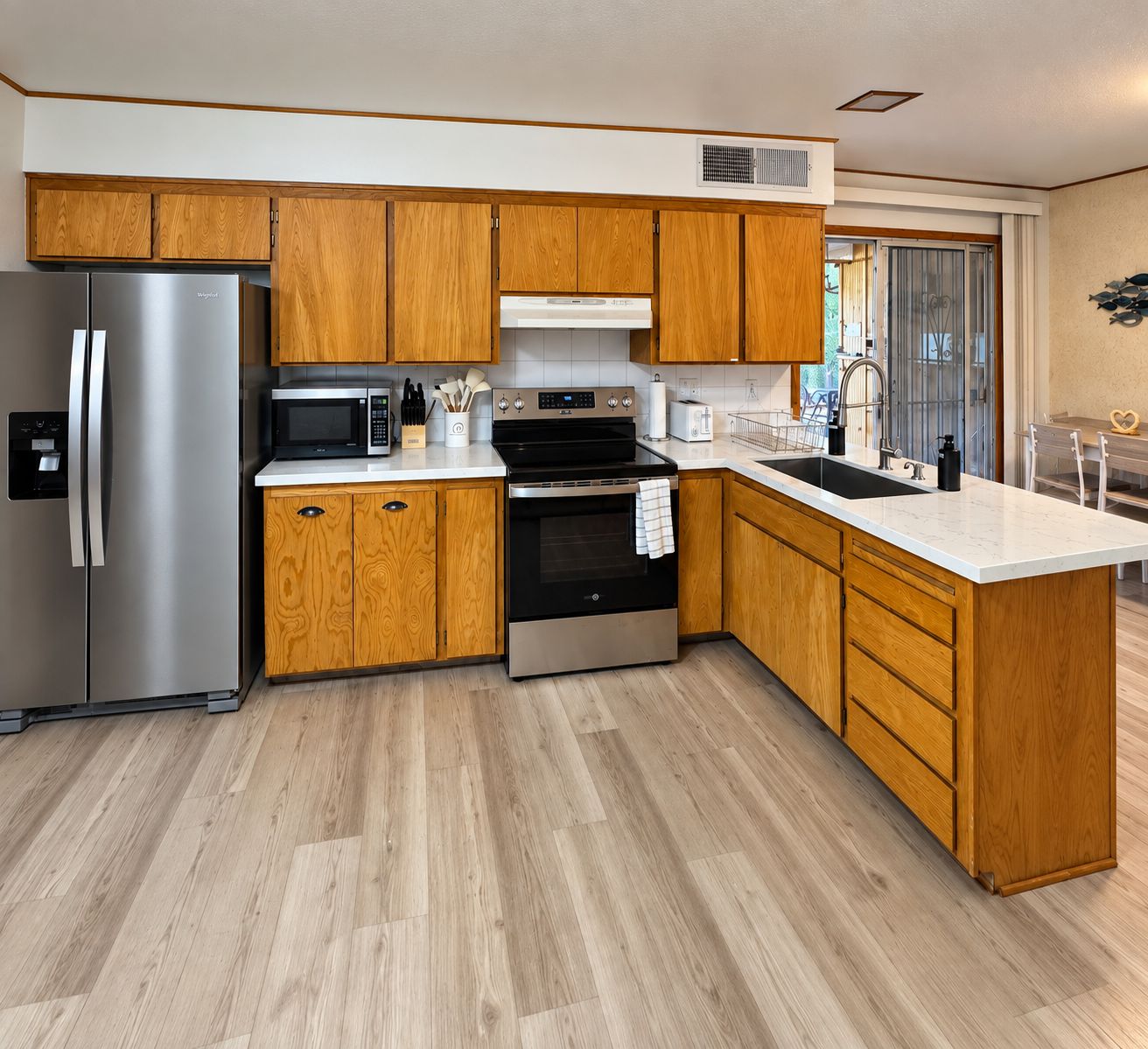 A modern kitchen with wooden cabinets, stainless steel appliances, and a large island.