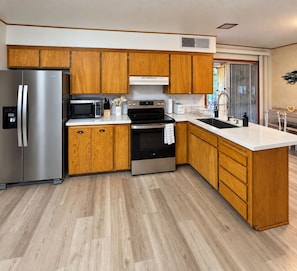 A modern kitchen with wooden cabinets, stainless steel appliances, and a large island.