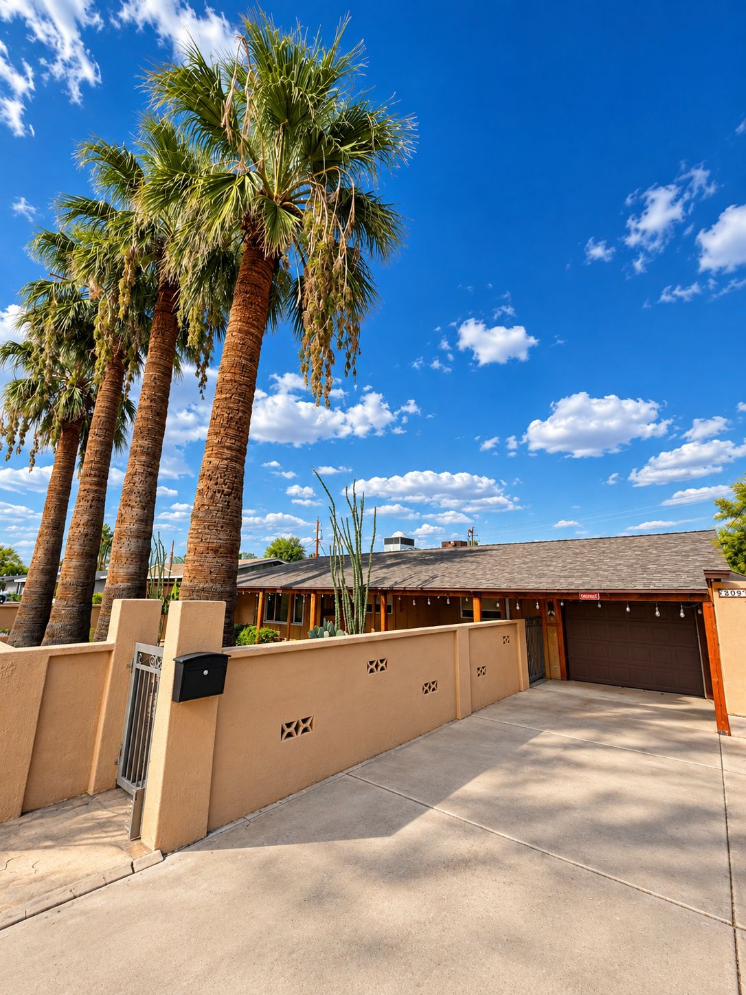 A residential property with a garage, palm trees, and a clear blue sky.