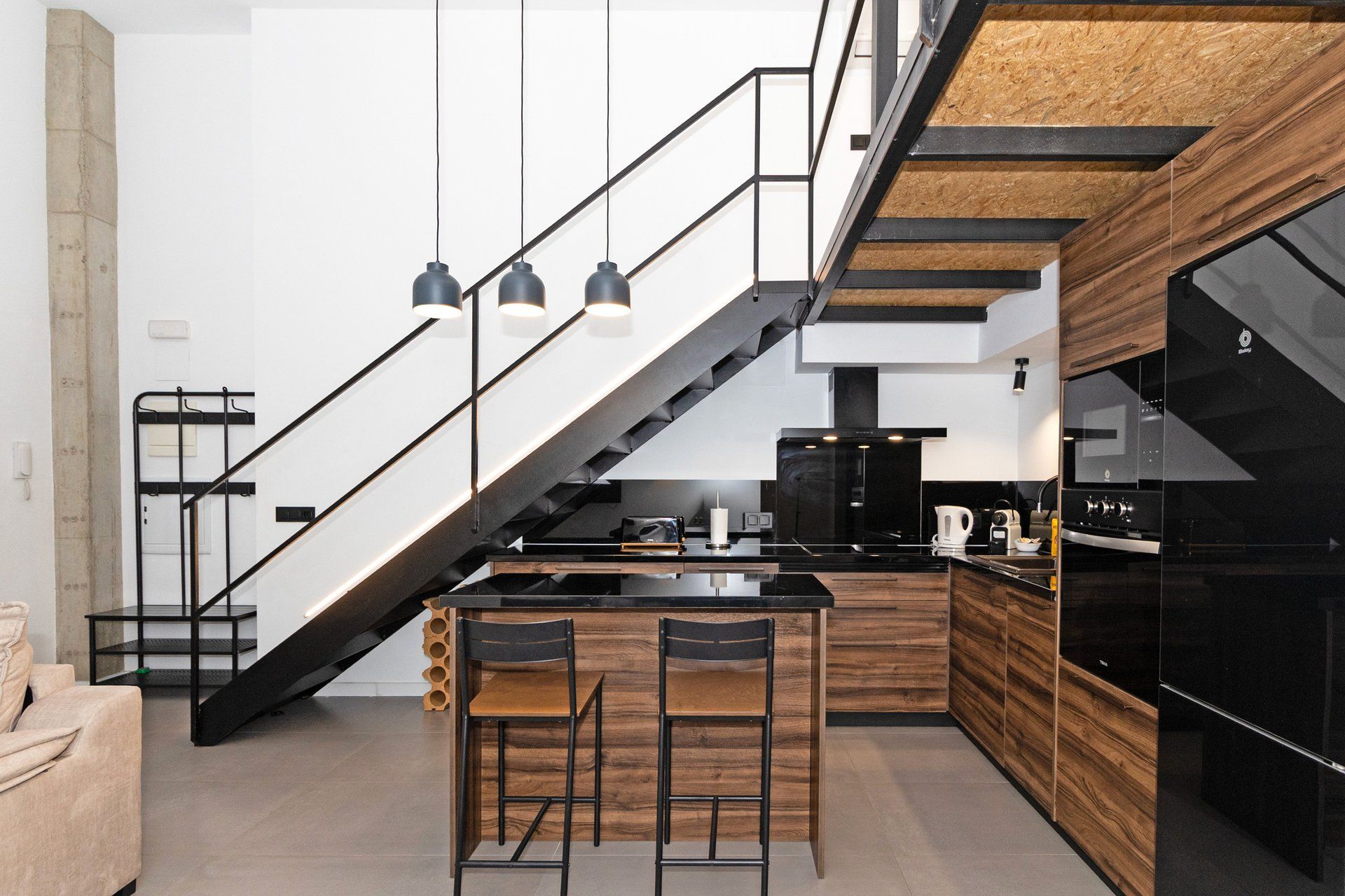 Una cocina moderna con una isla central, electrodomésticos negros y una pared de acento de madera.