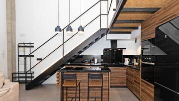 Una cocina moderna con una isla central, electrodomésticos negros y una pared de acento de madera.