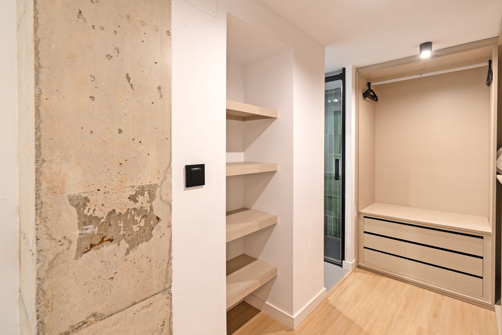 Una habitación con pared blanca, suelo de madera y armario empotrado con puertas correderas.