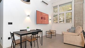 Una sala de estar moderna con comedor, un sofá, un televisor y un ventanal con vistas.
