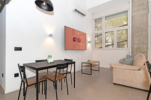 Un saló modern amb zona de menjador, un sofà, un televisor i una finestra amb vista.