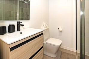 Un bagno moderno con un lavandino bianco, un rubinetto nero e un water.