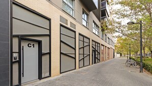 A modern building with large garage doors, a paved walkway, and a bicycle parked outside. - GuestReady - Apartment with Mezzanine in Benicalap (Valencia)