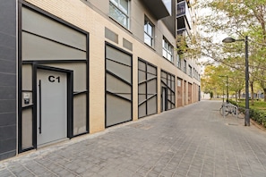 Un edificio moderno con ampie porte per garage, un vialetto lastricato e una bicicletta parcheggiata davanti.