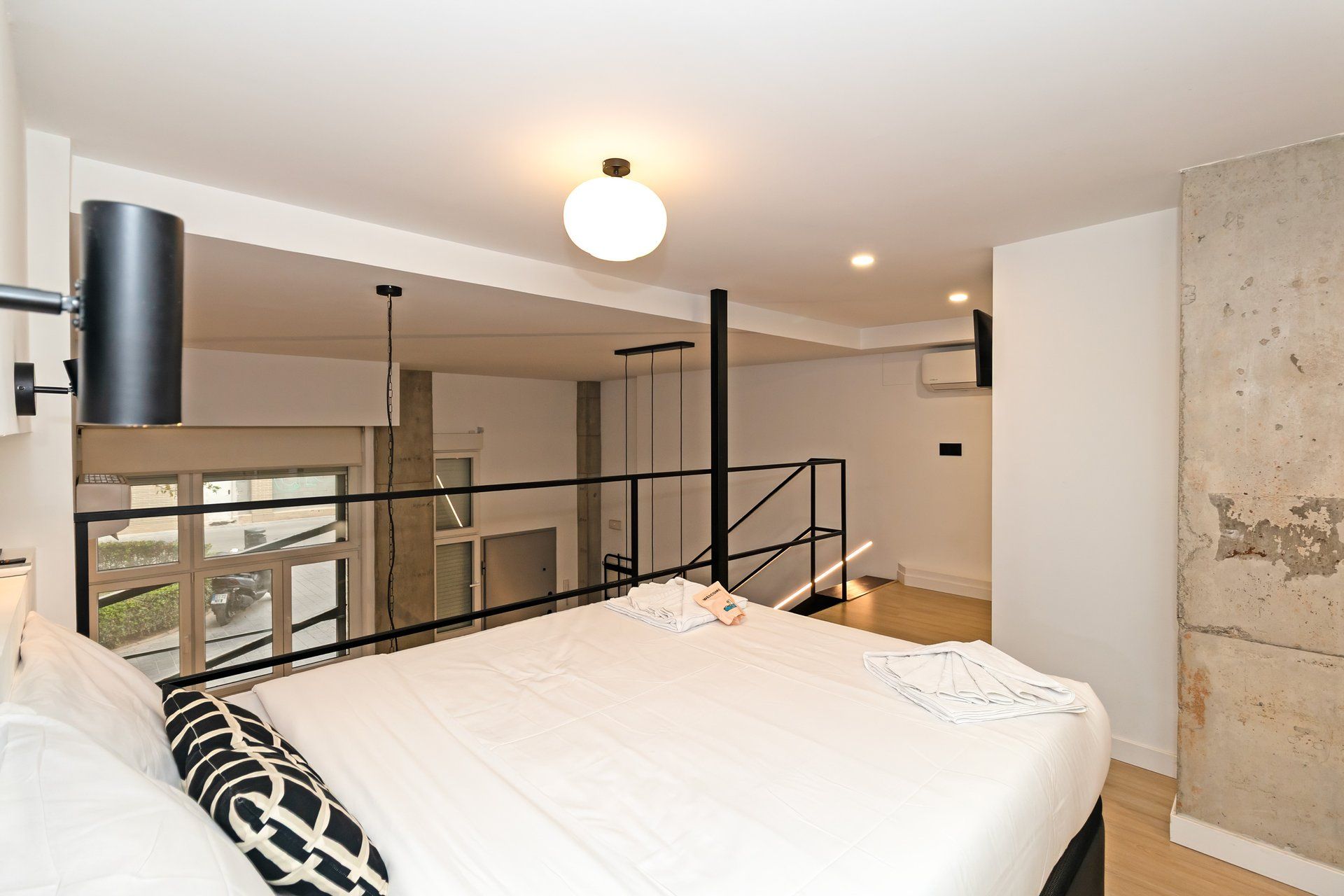 Una habitación de hotel moderna con una cama grande, un balcón y vista a la calle.