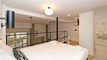 Una habitación de hotel moderna con una cama grande, un balcón y vista a la calle.