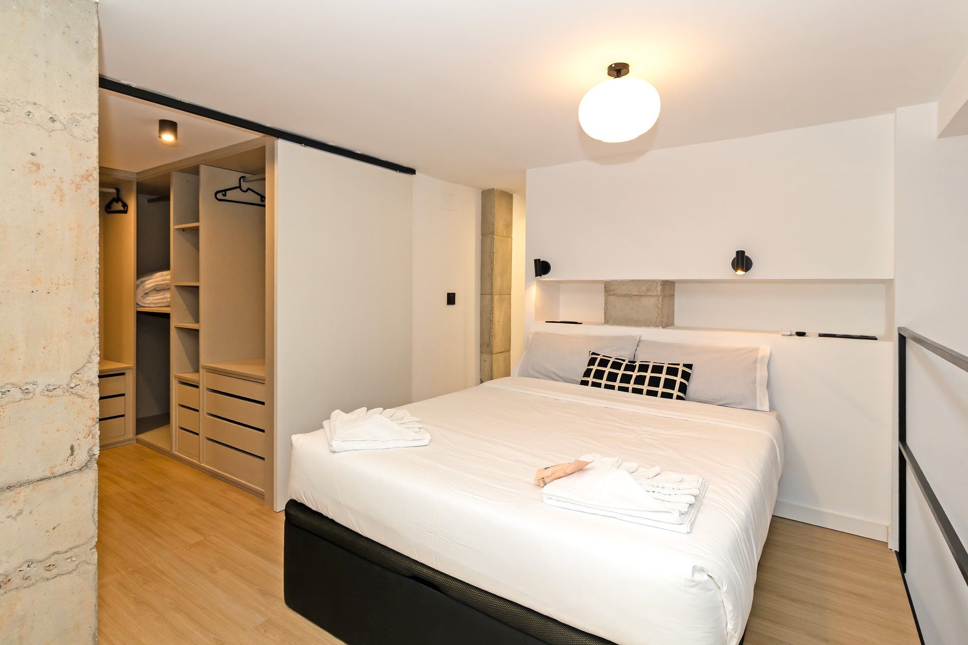 Un dormitorio con cama, armario y luz en el techo.