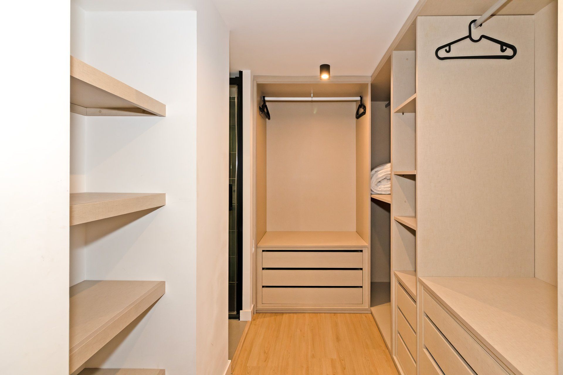 Un armario vestidor con estantes abiertos, una barra para colgar ropa y un closet con puerta corredera.
