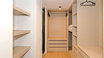 Un armario vestidor con estantes abiertos, una barra para colgar ropa y un closet con puerta corredera.
